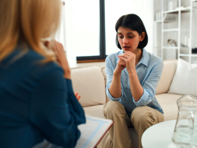 Joven mujer deprimida hablando con una psicóloga durante la sesión, salud mental. Mujer discutiendo problemas con psicólogo.