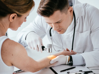 enfoque selectivo del dermatólogo que examina la mano de la mujer con dermatoscopio