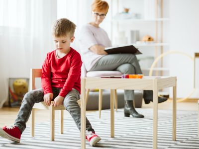 Niño con autismo sentado en una silla en un salón de clases en terapia