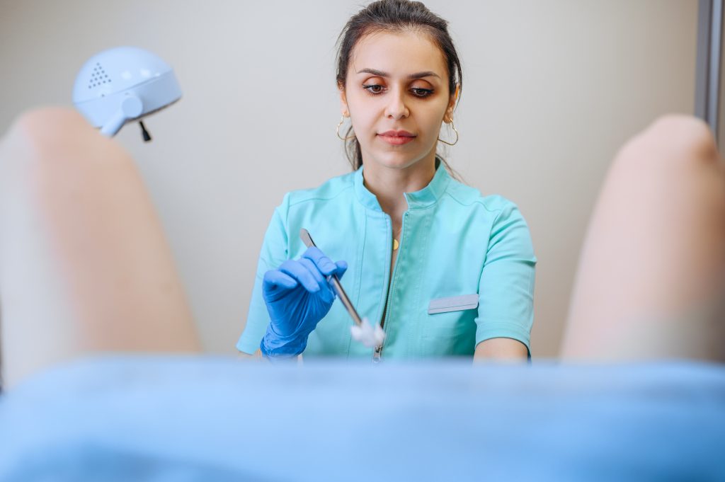 La ginecóloga sostiene un tampón de algodón, paciente en silla. Examen ginecológico en clínica, diagnóstico o consulta ginecológica, examen. Doctor y mujer en el hospital