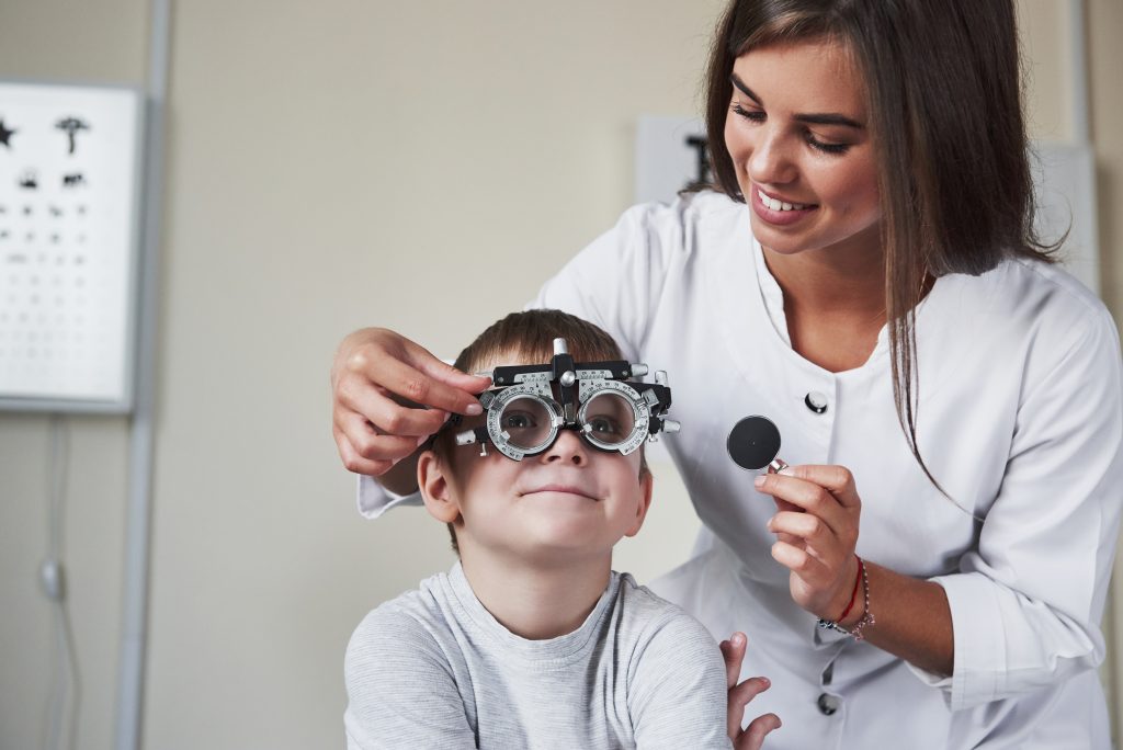 Doctor sintonizando el foróptero para determinar la agudeza visual del niño.