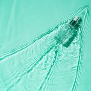 Suero hidratante con ácido hialurónico en una botella transparente con una pipeta sobre fondo azul agua Fondo médico para el cuidado de la piel de belleza. El concepto de hidratación express rápida